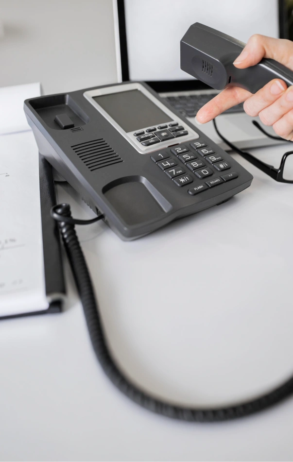 Hand picking up the handset of a VoIP desk phone
